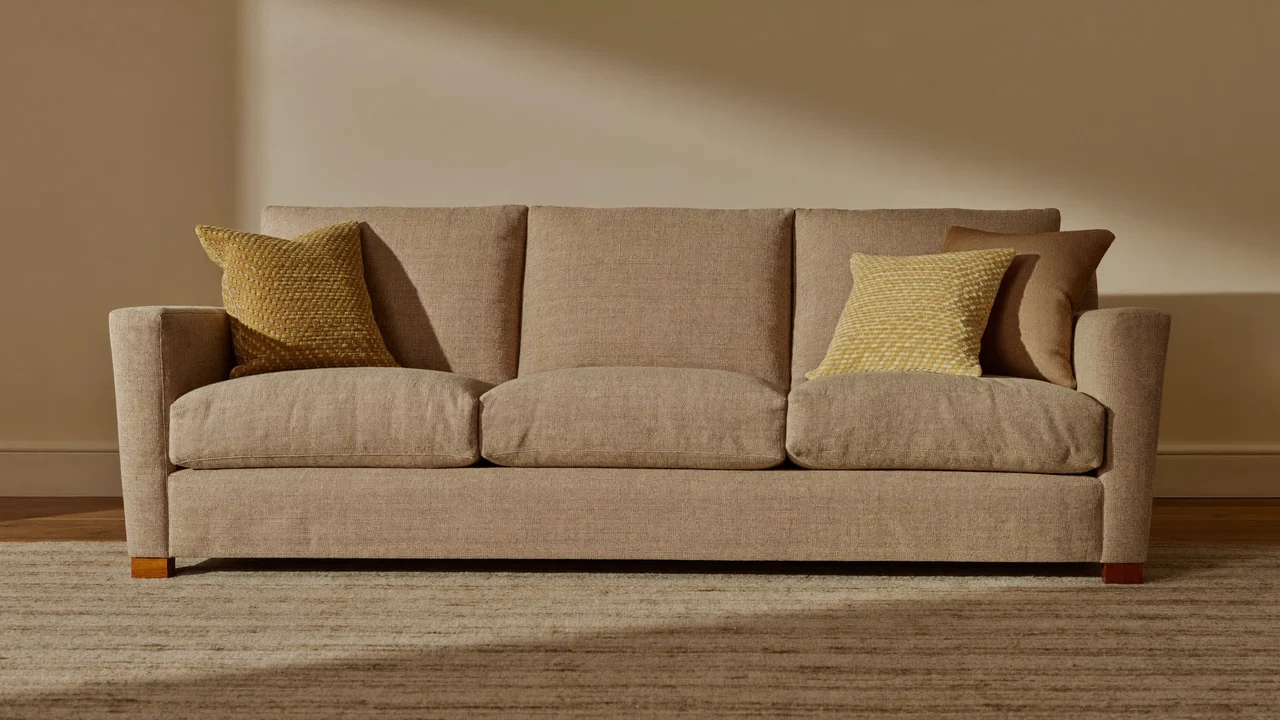 Dreisitzer-Sofa mit hellem Webstoffbezug in einem gestalteten Wohnraum
