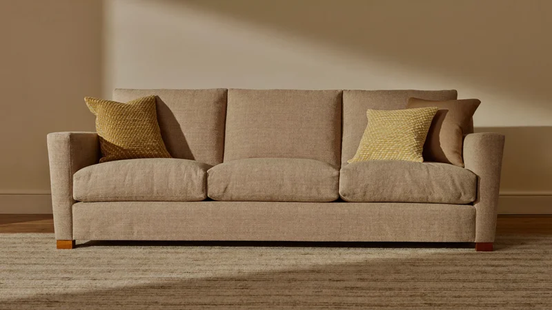 Dreisitzer-Sofa mit hellem Webstoffbezug in einem gestalteten Wohnraum